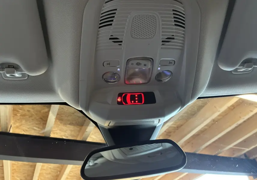 Vue intérieure du plafonnier gris clair du Peugeot 3008 noir, avec commandes d’éclairage et miroir rétro réfléchissant.