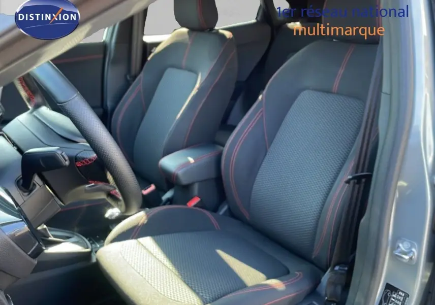 Vue intérieure côté conducteur du Ford Puma 2023, sièges tissu noir avec surpiqûres rouges et volant cuir perforé.