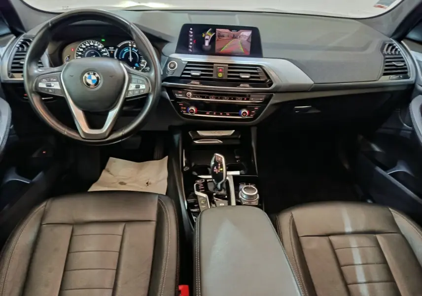 Vue intérieure avant du BMW X3 xDrive30e 2020, tableau de bord noir avec écran central et volant cuir multifonctions.