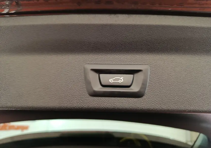 Bouton de fermeture électrique du coffre sur la partie intérieure du hayon d’un BMW X3 gris foncé.