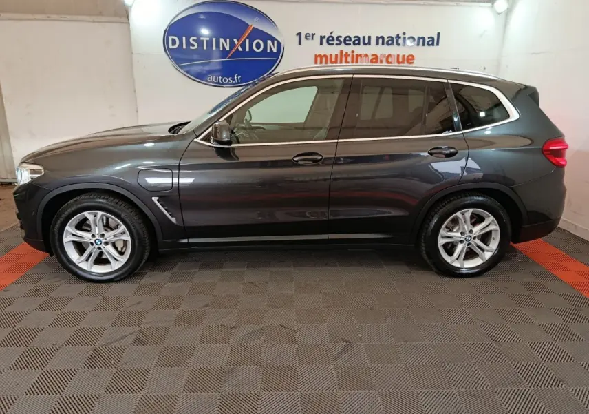 Profil droit d'un BMW X3 xDrive30e gris foncé hybride rechargeable, avec jantes alliage et prises de recharge visibles.