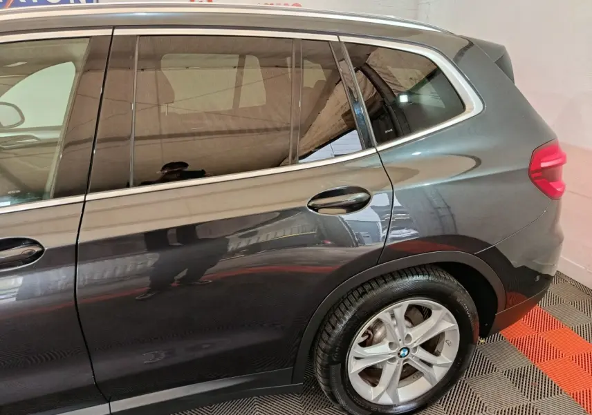 Vue côté droit arrière d’un BMW X3 xDrive30e gris foncé avec jante alliage et feux arrière LED visibles.