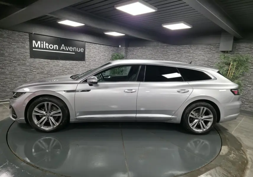 Volkswagen Arteon Shooting Brake gris métallisé vue de profil côté gauche en intérieur avec jantes alliage 18 pouces.