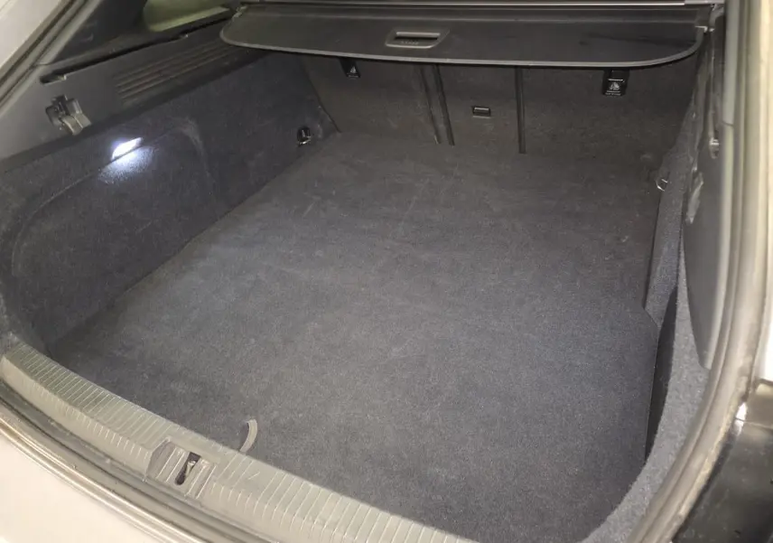 Coffre spacieux et propre du Volkswagen Arteon Shooting Brake gris, vu de l'arrière avec éclairage intérieur allumé.