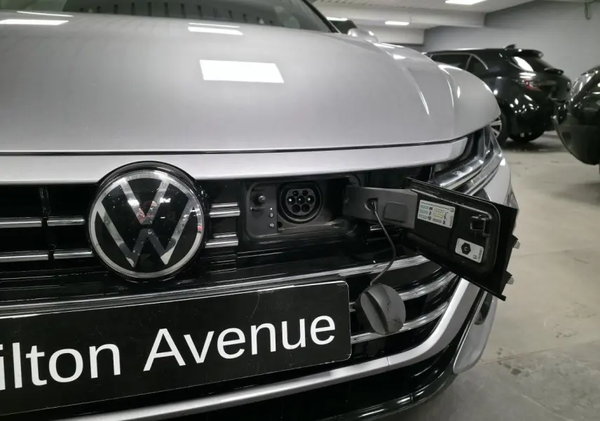 Vue rapprochée avant d’un Volkswagen Arteon gris avec prise de recharge hybride ouverte sur la calandre.