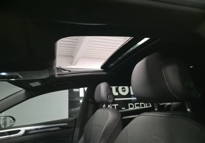 Vue intérieure du toit ouvrant coulissant en verre et des sièges avant noirs avec surpiqûres blanches du Volkswagen Arteon Shooting Brake R-Line.