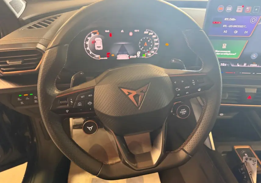 Vue intérieure centrée sur le volant cuir noir perforé de la CUPRA Formentor avec tableau de bord digital et écran tactile.