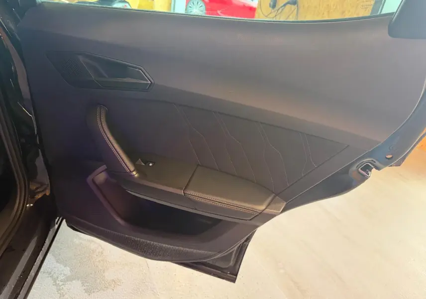 Vue intérieure de la porte arrière gauche noire du CUPRA Formentor 2025 avec garniture tissu et surpiqûres contrastées.