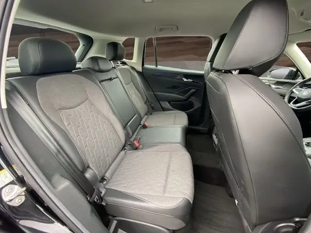 Vue intérieure côté gauche des sièges arrière gris et noirs du Volkswagen Tiguan 2024 avec accoudoirs centraux et finitions cuir.