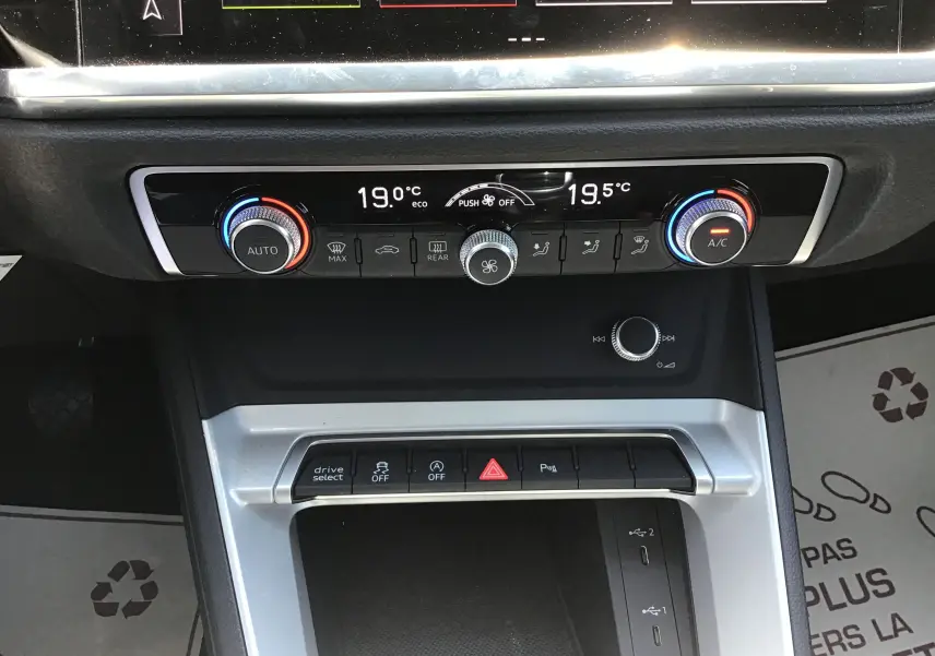 Gros plan sur la console centrale de l'Audi Q3 Sportback 2024, montrant les commandes de climatisation et les boutons de fonction.