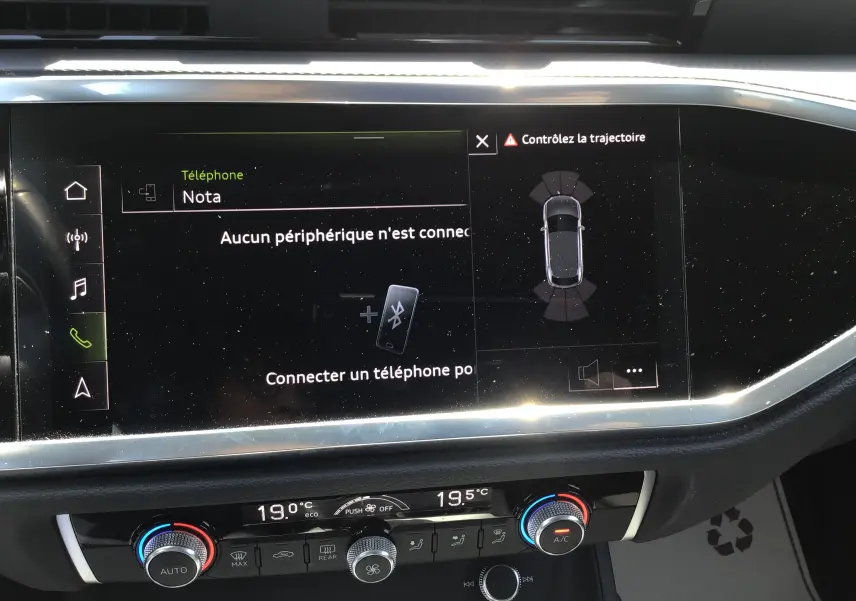Vue rapprochée de l’écran tactile central et de la console de climatisation du tableau de bord de l’Audi Q3 Sportback gris clair 2024.