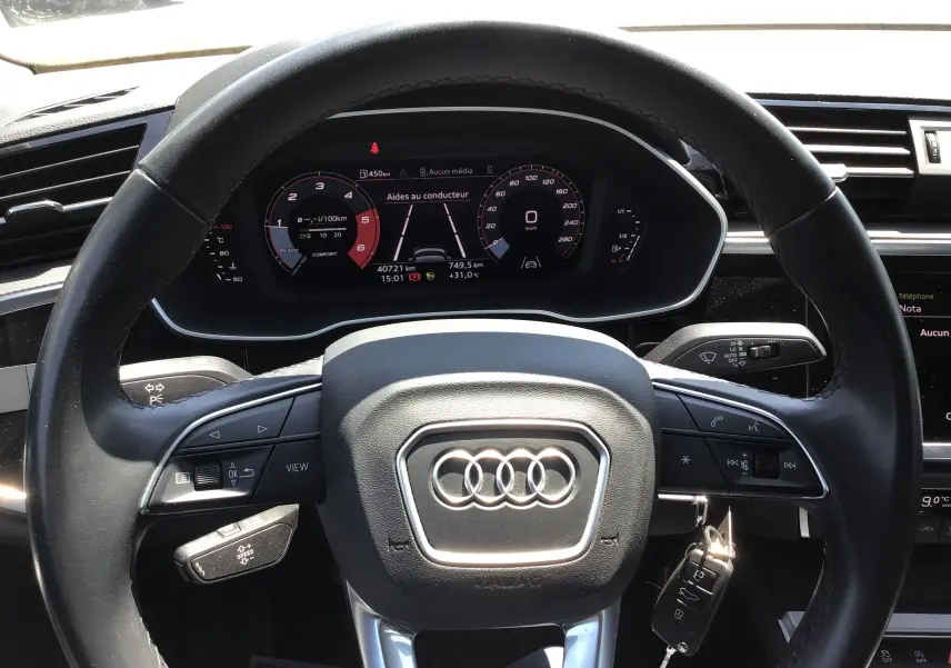 Vue rapprochée du volant noir et du tableau de bord numérique d’un Audi Q3 Sportback gris clair métal 2024.