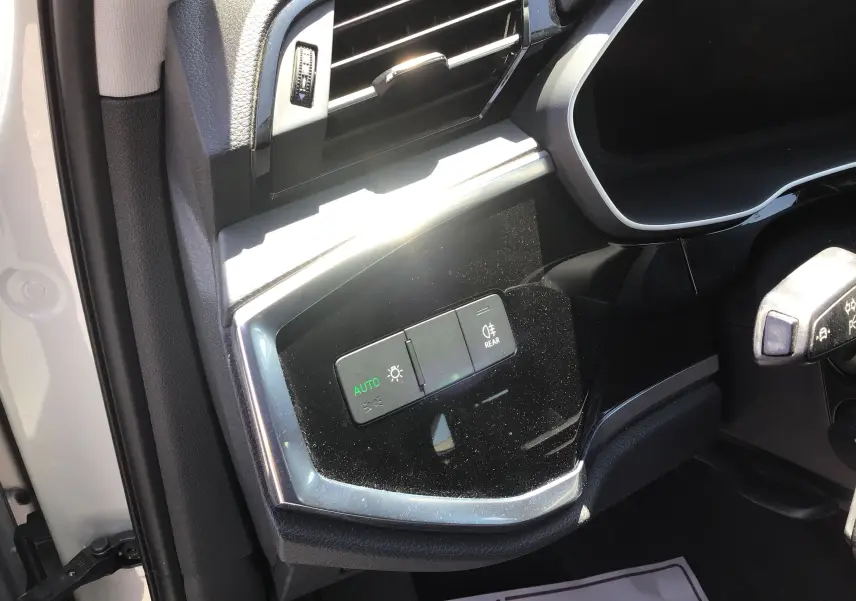 Gros plan sur les commandes d’éclairage côté gauche du tableau de bord d’un Audi Q3 Sportback gris clair 2024.