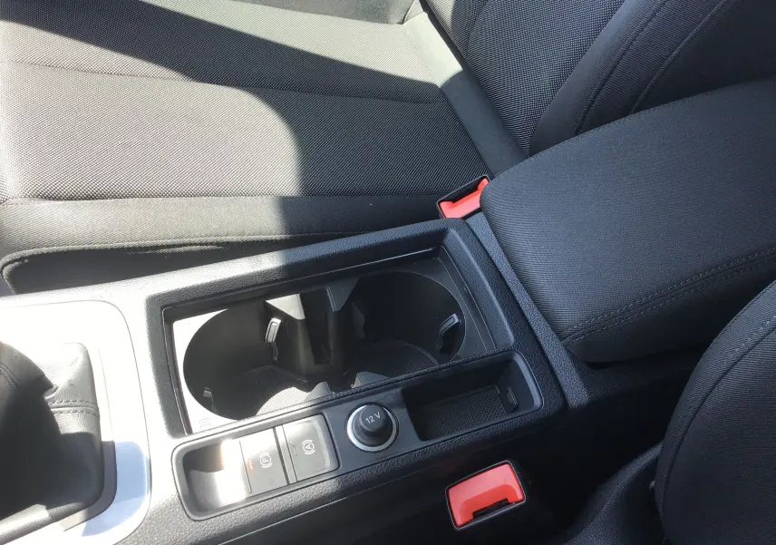 Gros plan sur la console centrale noire avec porte-gobelets et accoudoir du Audi Q3 Sportback gris clair 2024.