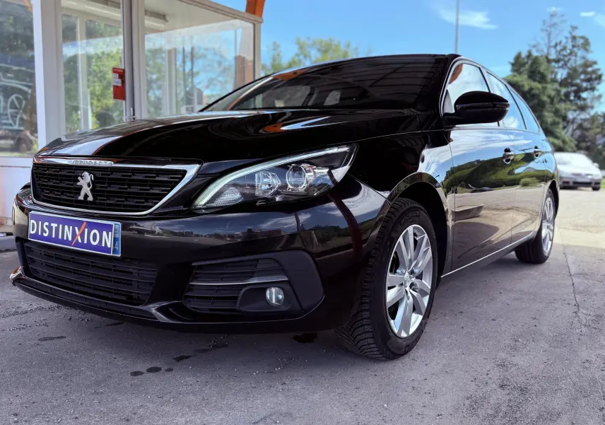 Peugeot 308 SW noire métal vue 3/4 avant droit sous abri avec jantes alliage et calandre distinctive