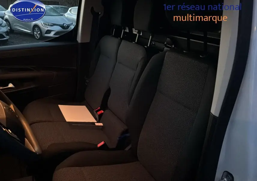 Vue intérieure côté conducteur du Citroën Berlingo Fourgon blanc 2025, montrant les sièges avant noirs et la cloison pleine arrière.