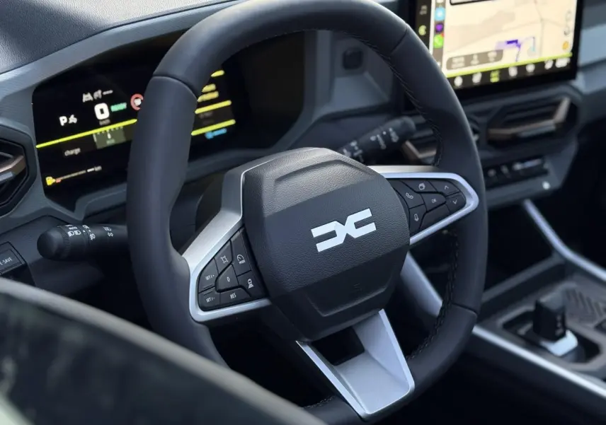 Gros plan sur le volant noir et argenté du Dacia Bigster 2026 avec tableau de bord numérique et écran tactile visible.