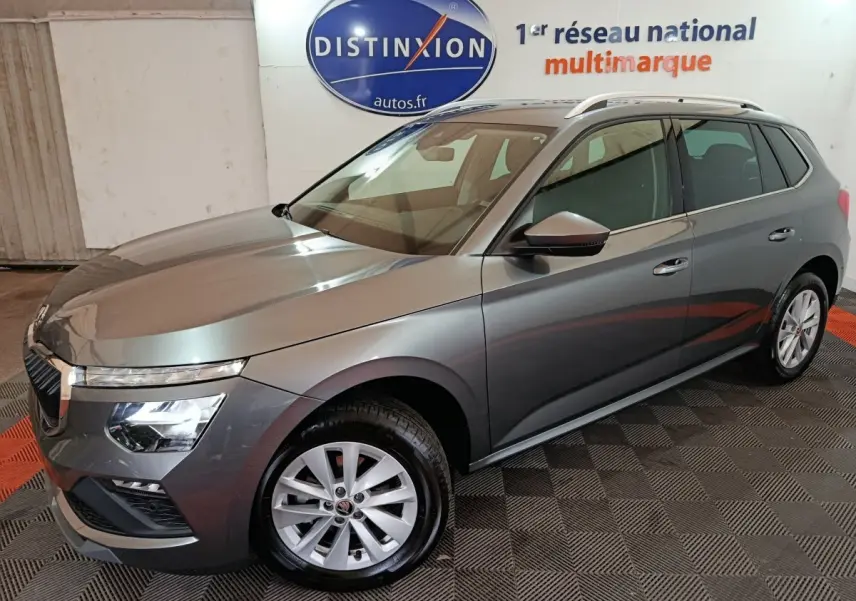 Vue 3/4 avant droit d'un Skoda Kamiq gris clair avec phares LED et jantes alliage dans un showroom.