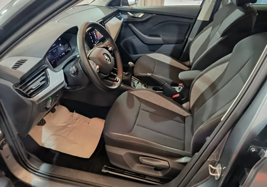 Vue intérieure côté conducteur du Skoda Kamiq 2024 gris clair, volant cuir multifonctions et tableau de bord numérique.