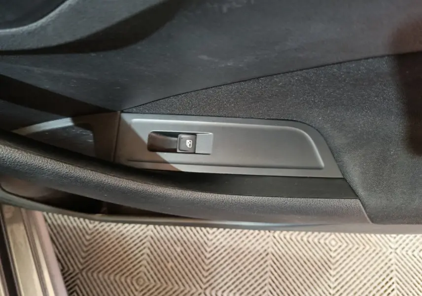 Gros plan sur le bouton de lève-vitre électrique côté conducteur dans l'intérieur noir du Skoda Kamiq gris clair 2024.