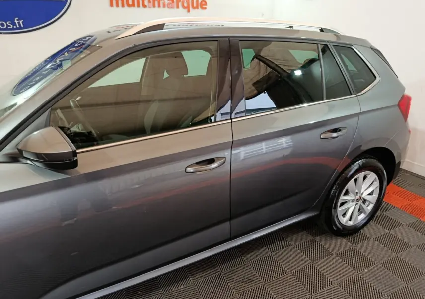Vue latérale droite d'un Skoda Kamiq gris clair avec rétroviseur et poignées assortis, roues en alliage.
