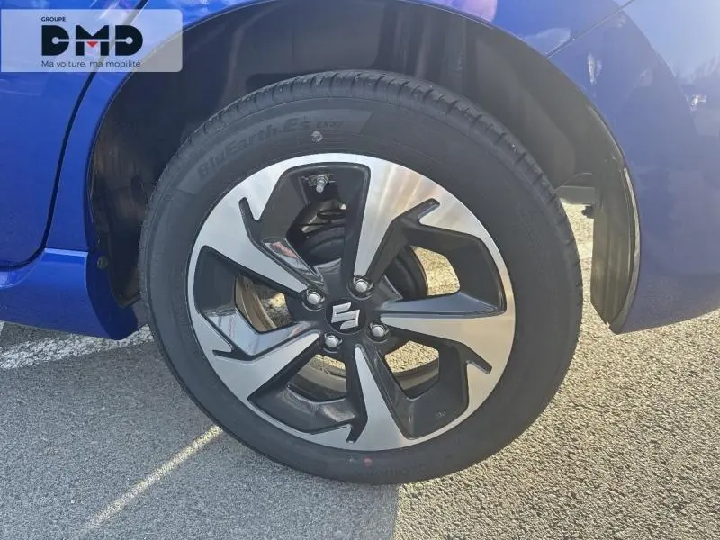 Gros plan sur la roue avant droite de la Suzuki Swift 1.2 Hybrid en bleu Frontier Pearl Metal avec jante alu bicolore.