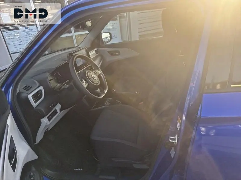 Intérieur avant droit d'une Suzuki Swift 1.2 Hybrid bleue, montrant siège tissu et volant multifonction cuir.