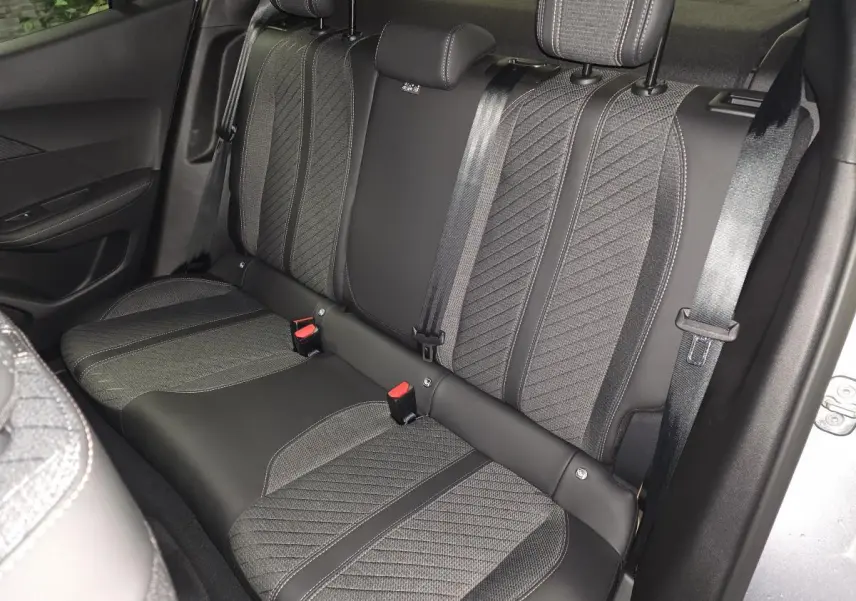 Vue intérieure côté droit sur la banquette arrière gris foncé avec surpiqûres et ceintures de sécurité du Peugeot 2008 hybride 2025.