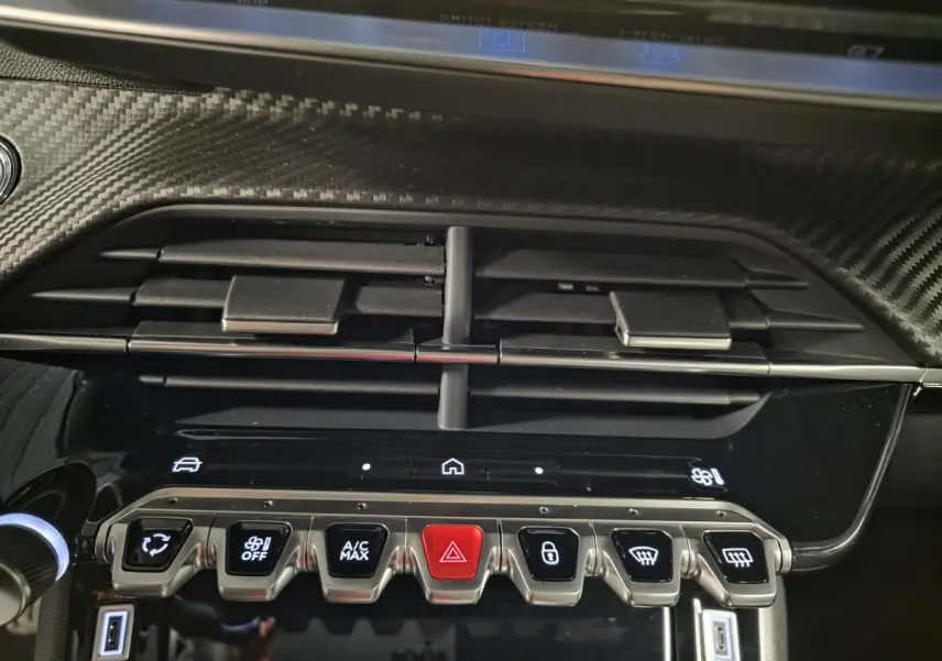 Détail de la console centrale du Peugeot 2008 gris 2025, avec aérateurs et rangée de boutons fonctionnels éclairés.