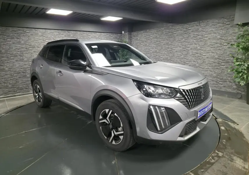 Peugeot 2008 gris en 3/4 avant droit, avec calandre noire à marquage vertical et jantes alliage bi-ton.