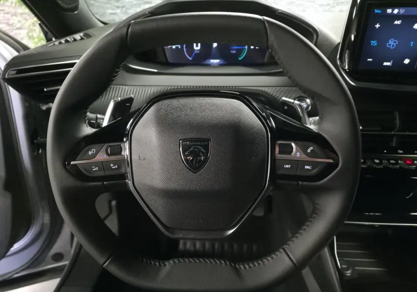 Vue rapprochée du volant compact noir de la Peugeot 2008 2025 avec commandes multimédia intégrées et tableau de bord numérique.