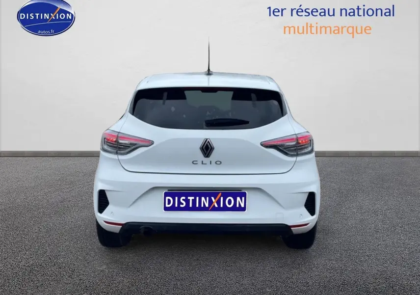 Vue arrière d'une Renault Clio V blanche avec feux LED et logo Renault visible sur un sol gris.