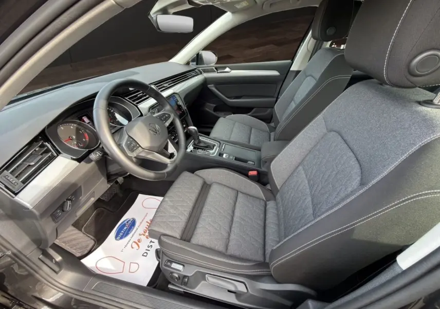 Vue intérieure côté conducteur de la Volkswagen Passat 2.0 TDI 2022 avec sièges tissu gris et tableau de bord moderne.