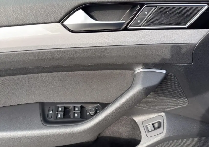 Gros plan sur la porte côté conducteur de la Volkswagen Passat gris foncé, avec commandes électriques et poignée intégrée.