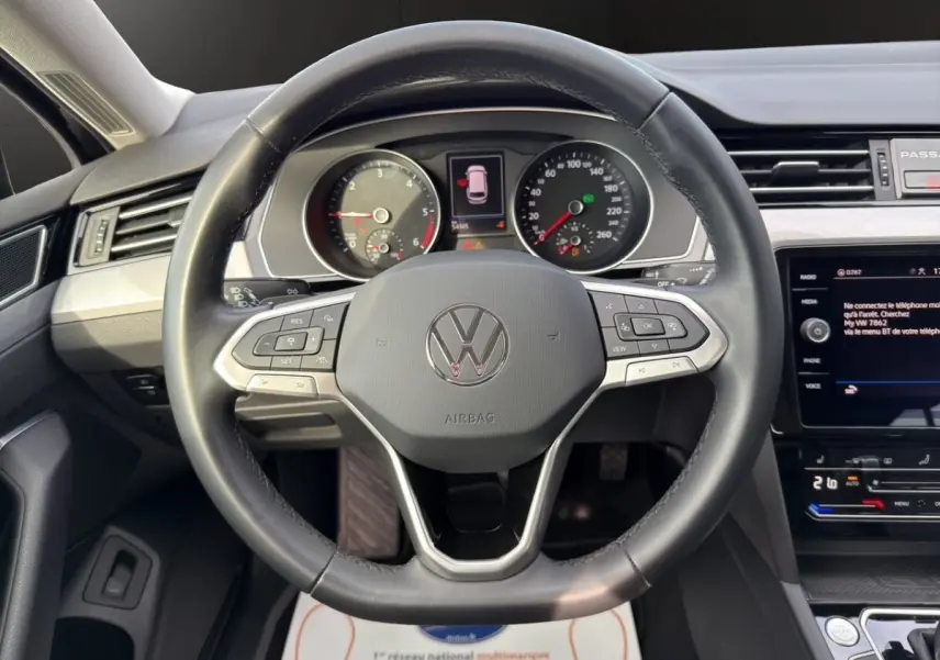 Vue intérieure centrée sur le volant cuir noir et le tableau de bord numérique de la Volkswagen Passat 2.0 TDI 2022.