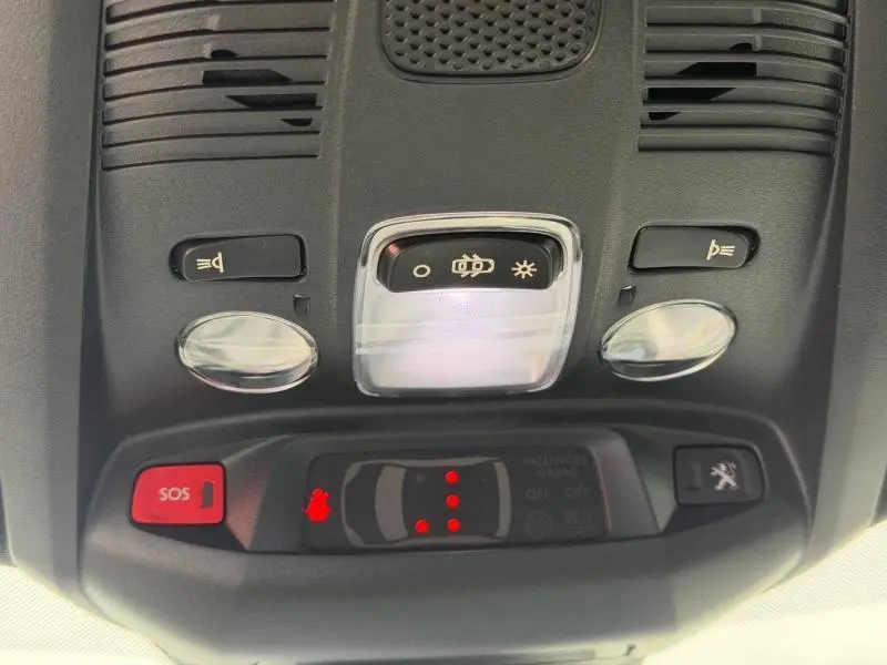 Vue en gros plan du panneau de commandes de toit intérieur du Peugeot 3008 gris titane, avec boutons d’éclairage et alerte SOS.