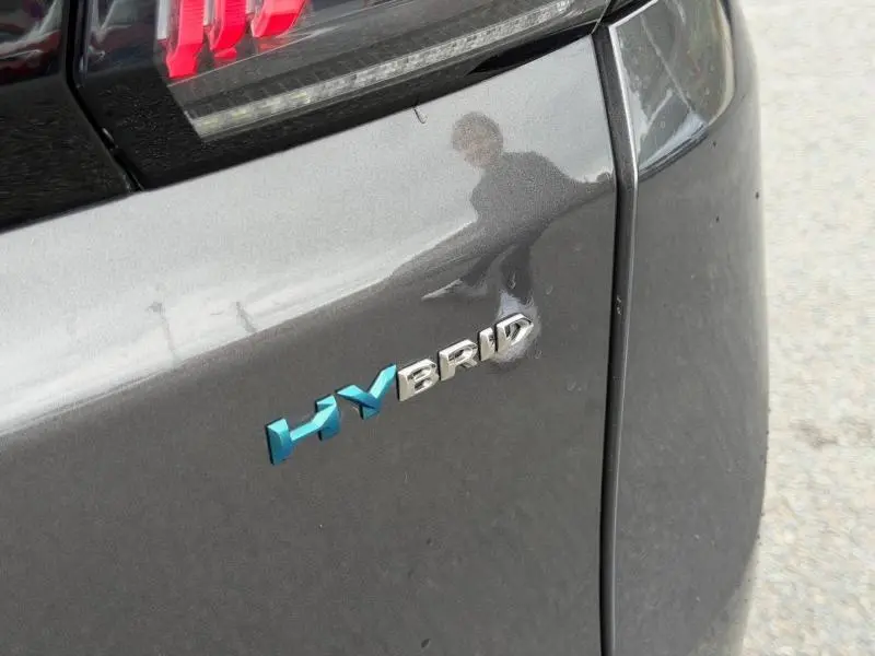 Gros plan sur l'arrière droit gris titane du Peugeot 3008 hybride rechargeable avec logo HYBRID bleu et chrome.