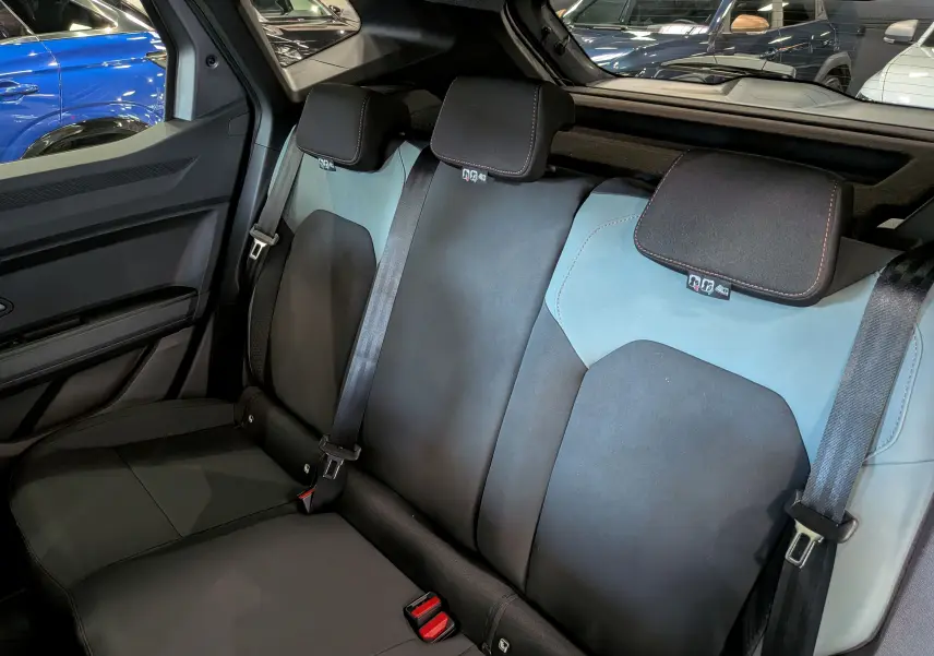 Vue intérieure sur la banquette arrière du Dacia Duster 2026 gris schiste, avec sièges bicolores noir et bleu clair.