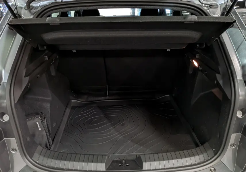 Coffre ouvert du Dacia Duster gris schiste 2026, vue arrière montrant l’espace de chargement avec tapis de protection noir.