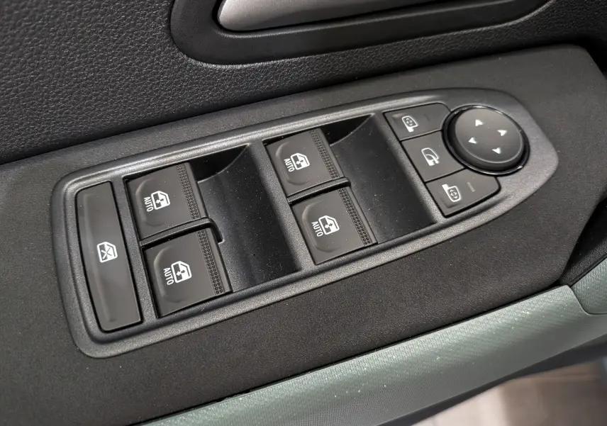Gros plan sur les commandes de lève-vitres et rétroviseurs électriques côté conducteur du Dacia Duster gris Schiste 2026.