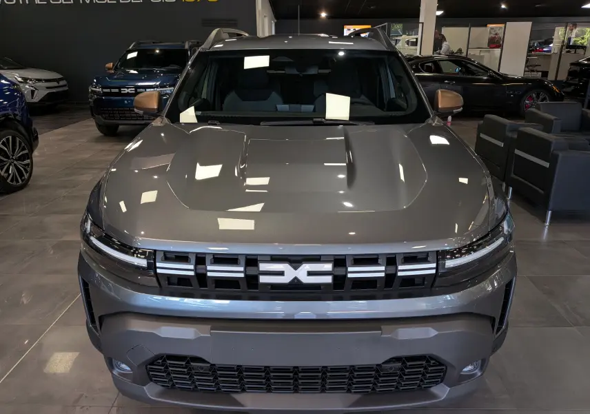 Vue avant frontale du Dacia Duster 2026 gris schiste avec calandre noire et logo central distinctif en concession.