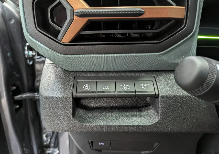 Gros plan sur les commandes noires et la grille d’aération avec insert marron du tableau de bord du Dacia Duster gris schiste.