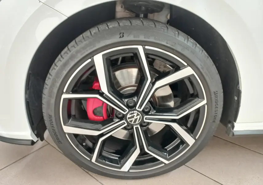 Gros plan sur la jante alliage 18'' noire et argentée avec étrier de frein rouge du côté gauche d'une Volkswagen Polo blanche.