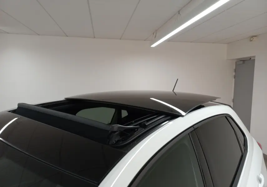 Vue rapprochée du toit ouvrant électrique noir ouvert sur une Volkswagen Polo GTI blanc pur, angle arrière droit.