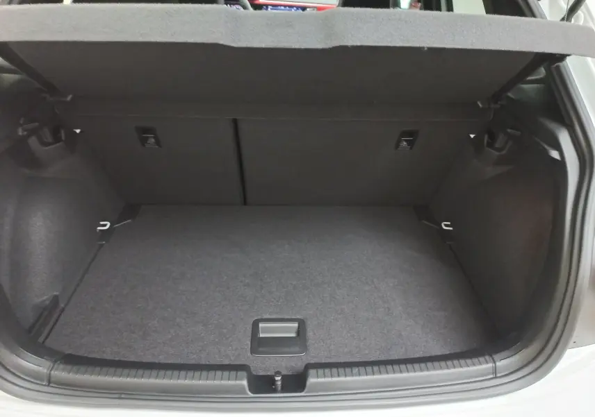 Vue du coffre ouvert d'une Volkswagen Polo blanche, montrant un espace de rangement propre et vide avec habillage gris.