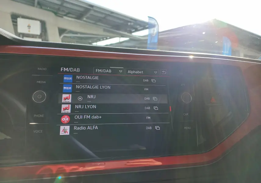 Écran tactile central de la Volkswagen Polo GTI 2024 avec interface radio FM/DAB et cadre décoratif rouge.