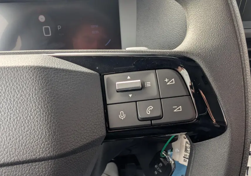 Gros plan sur les commandes au volant à droite du Peugeot Expert Fourgon noir, avec combiné numérique en arrière-plan.