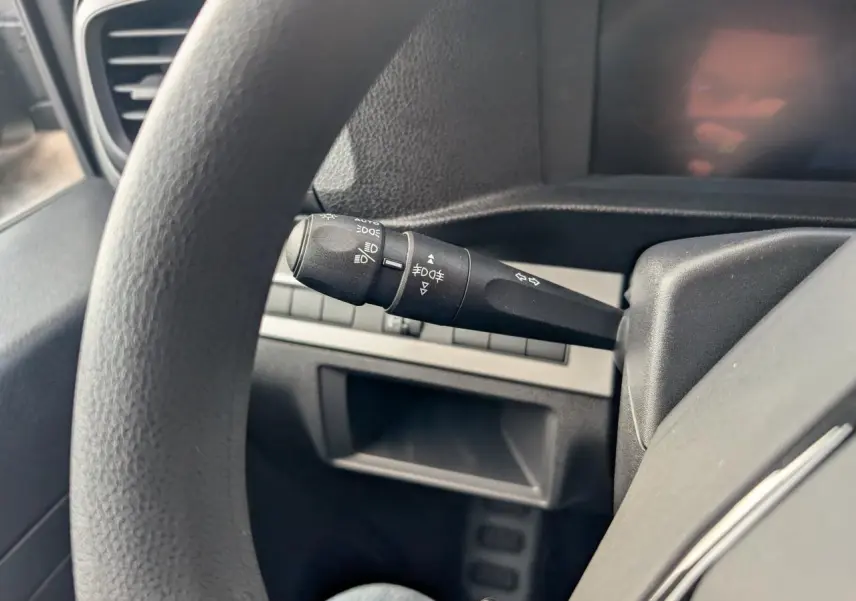 Détail de la commande de phares et clignotants côté gauche du volant dans l'habitacle noir du Peugeot Expert Fourgon 2025.