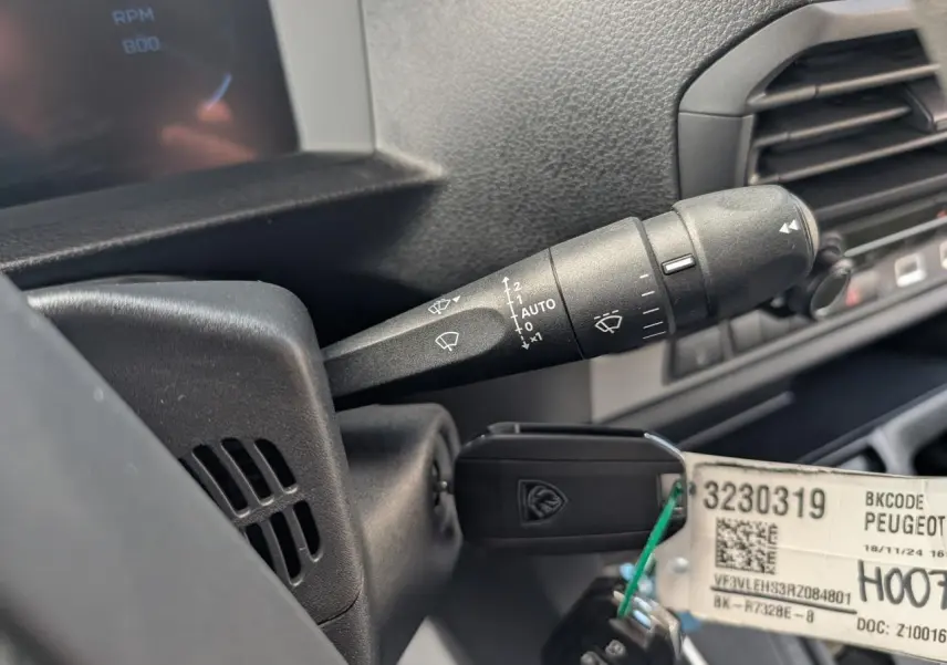 Gros plan sur la manette d’essuie-glace noire et la clé insérée dans le contacteur du Peugeot Expert Fourgon noir.