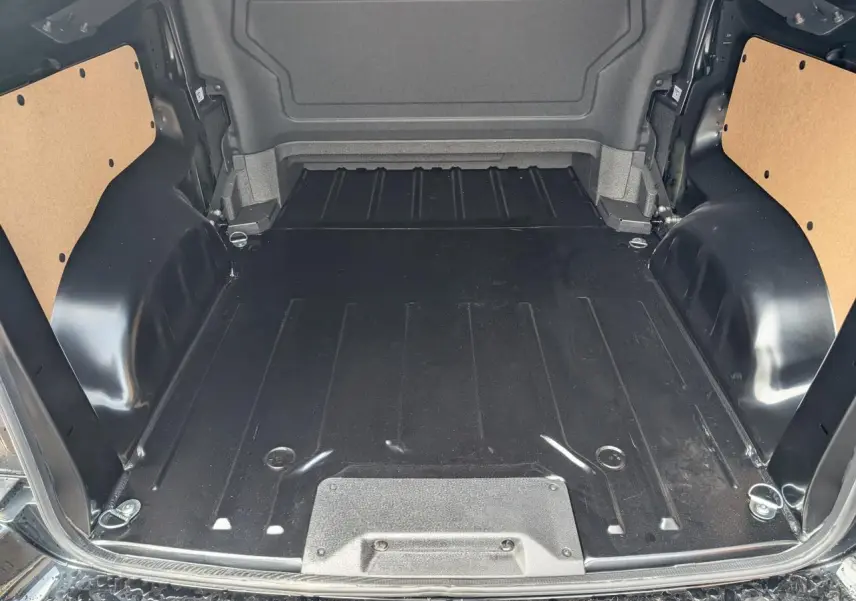 Espace de chargement noir du Peugeot Expert Fourgon 2025, vue arrière ouverte avec fixations et panneaux latéraux bois.